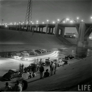 Drag racing and car exhibition on the Los Angeles Riverbed, under the classic Sixth Street Bridge. c. 1956
