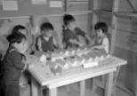 Nursery school children play with a scale model of their barracks at the Tule Lake Relocation Center, Newell, California, on September 11, 1942.