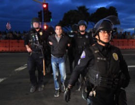 Shmuel Gonzales, activist historian, arrested at Counter-Protest of Alt-Right in Laguna Beach, Calif. Being extracted military-style by five police officers in riot gear after he was himself attacked by fascists.